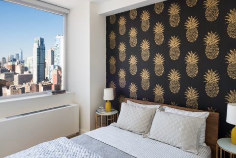 bedroom with accent wall and views of brooklyn and manhattan